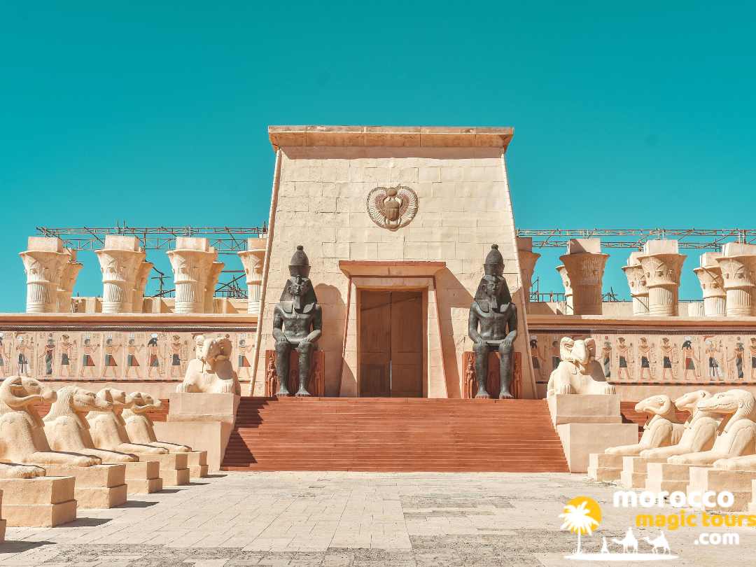 The grand Egyptian-style entrance gate featuring large pharaoh statues at Atlas Film Studios in Ouarzazate.