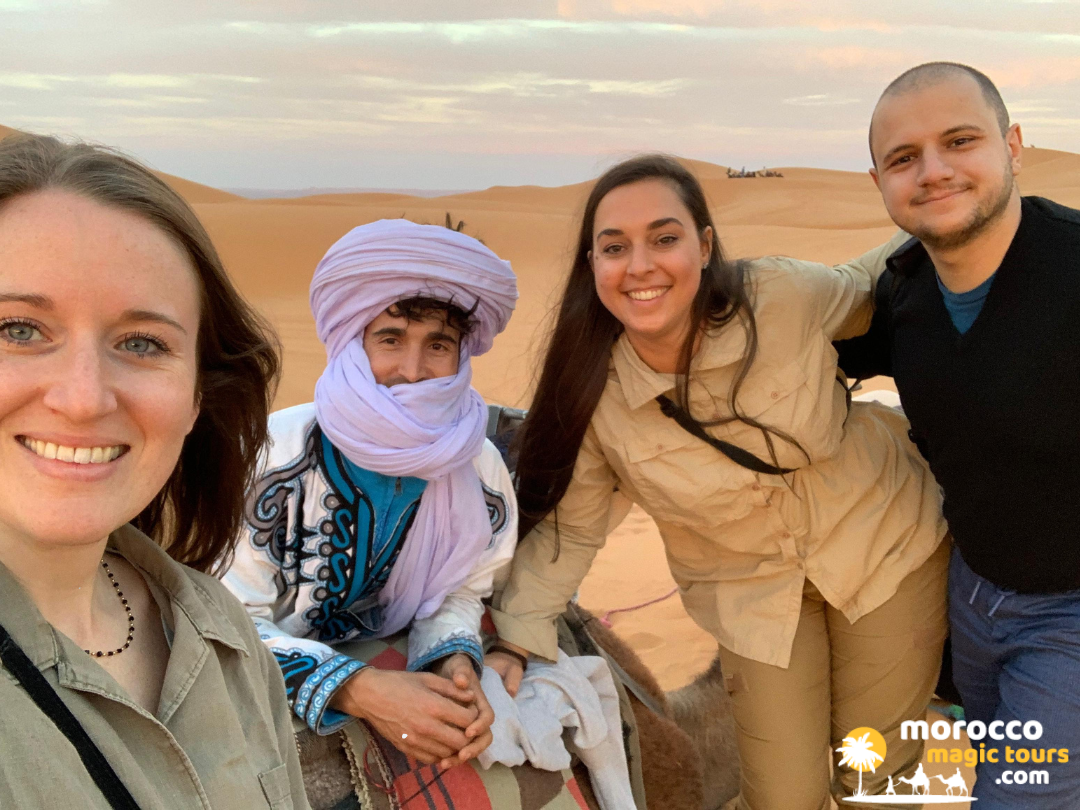 Happy travelers posing with our local Berber guide during a marrakech sahara desert tour