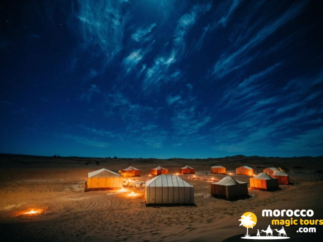 Traditional Berber luxury desert camp tents illuminated at night under a starry sky on a 6 days desert tour from Marrakech.