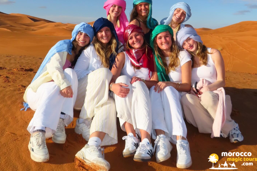 Group on a 7 day Morocco tour wearing turbans on the Sahara dunes