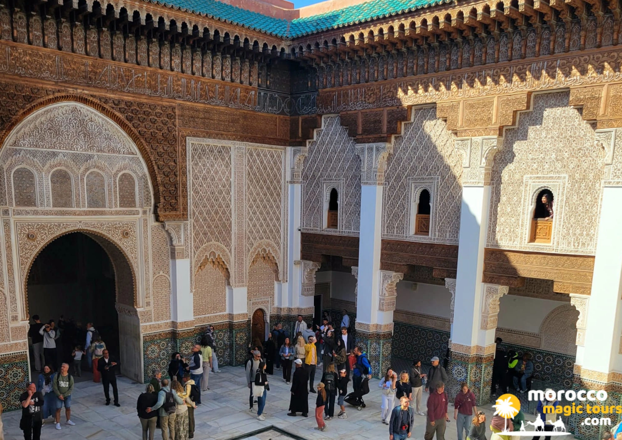 Tourists are touring the magnificent central courtyard of the historic Ben Youssef Madrasa in Marrakech on an 8 days from Casablanca tour.