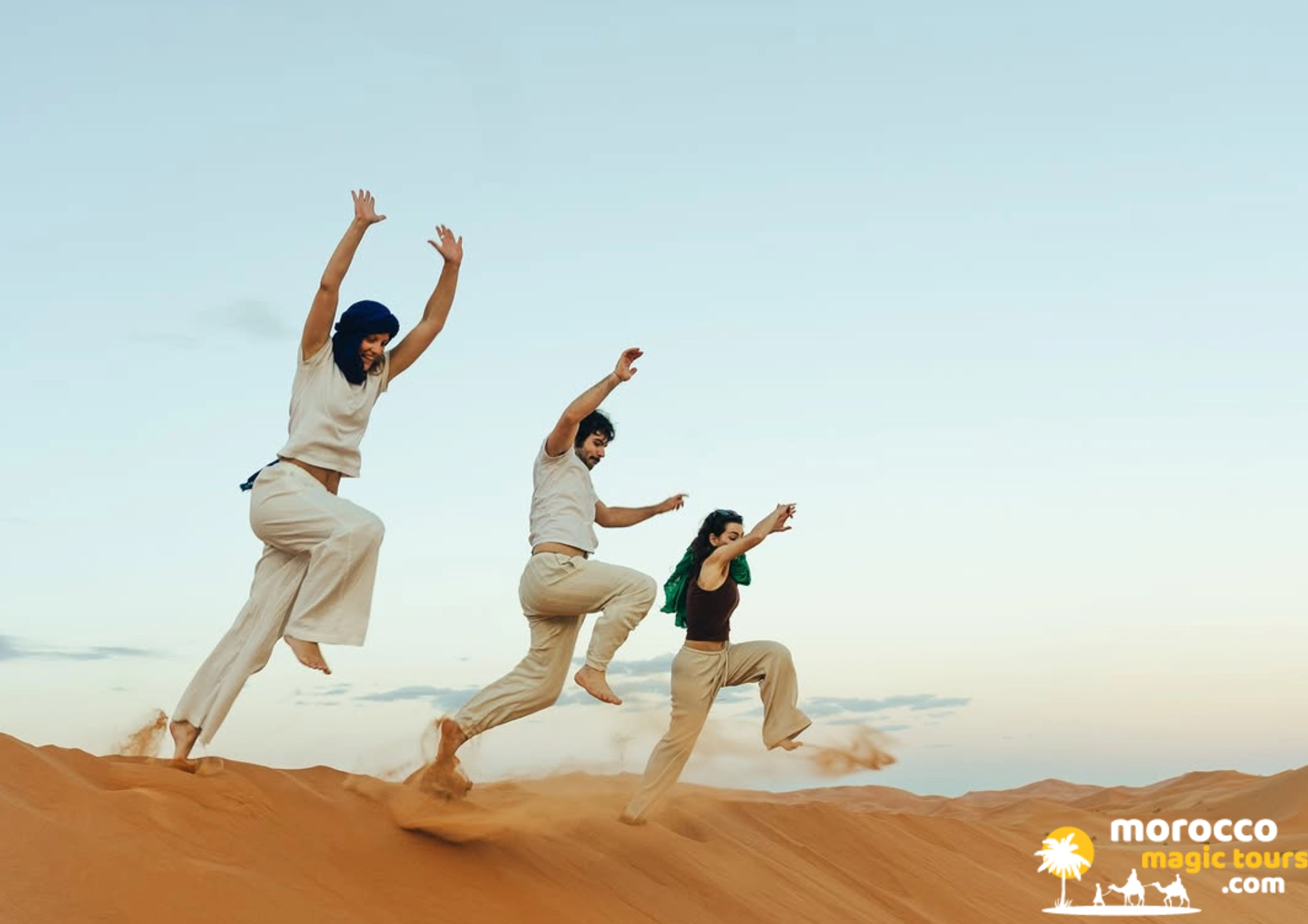 8 days tour from Casablanca to Merzouga sand dune with 3 friends jumping happily in the air.