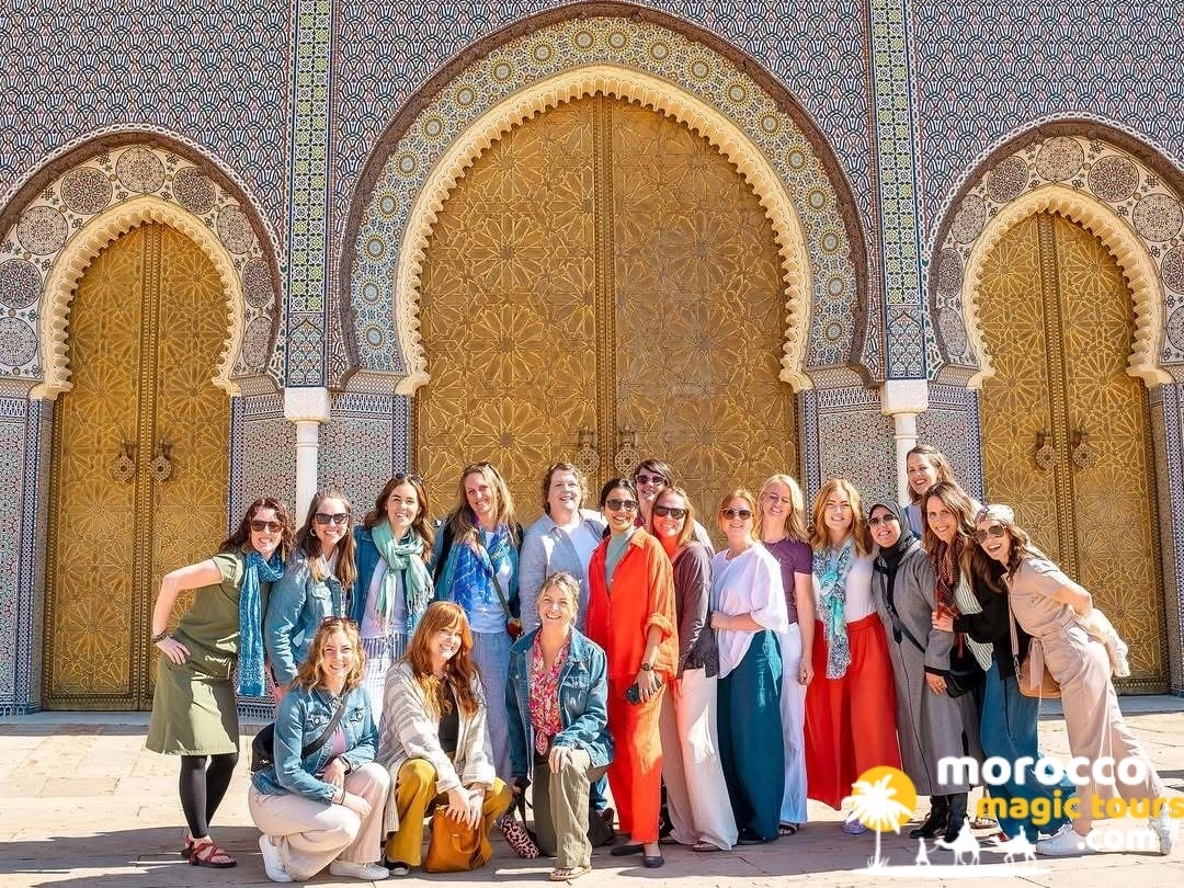 Un grupo de mujeres viajeras se encuentra frente a las ornamentadas puertas doradas del Palacio Real en Fez durante una excursión de Morocco Magic Tours.
